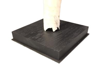     Détail de la fixation d'une dent de narval sur un socle en bois plat lesté d'une plaque métallique sur fond blanc