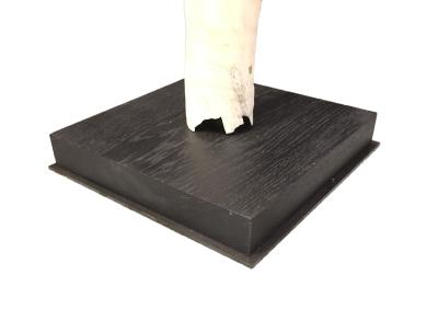 Détail de la fixation d'une dent de narval sur un socle en bois plat lesté d'une plaque métallique sur fond blanc