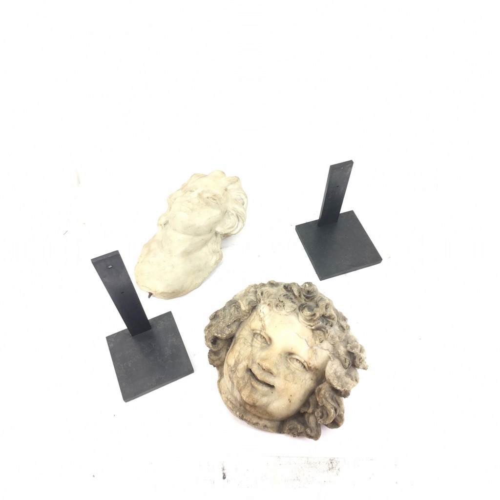 têtes sculptée à côté d'une présentoir et socle noir 