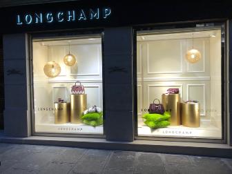 vitrine d'une boutique Longchamp la nuit, sac & présentoir 