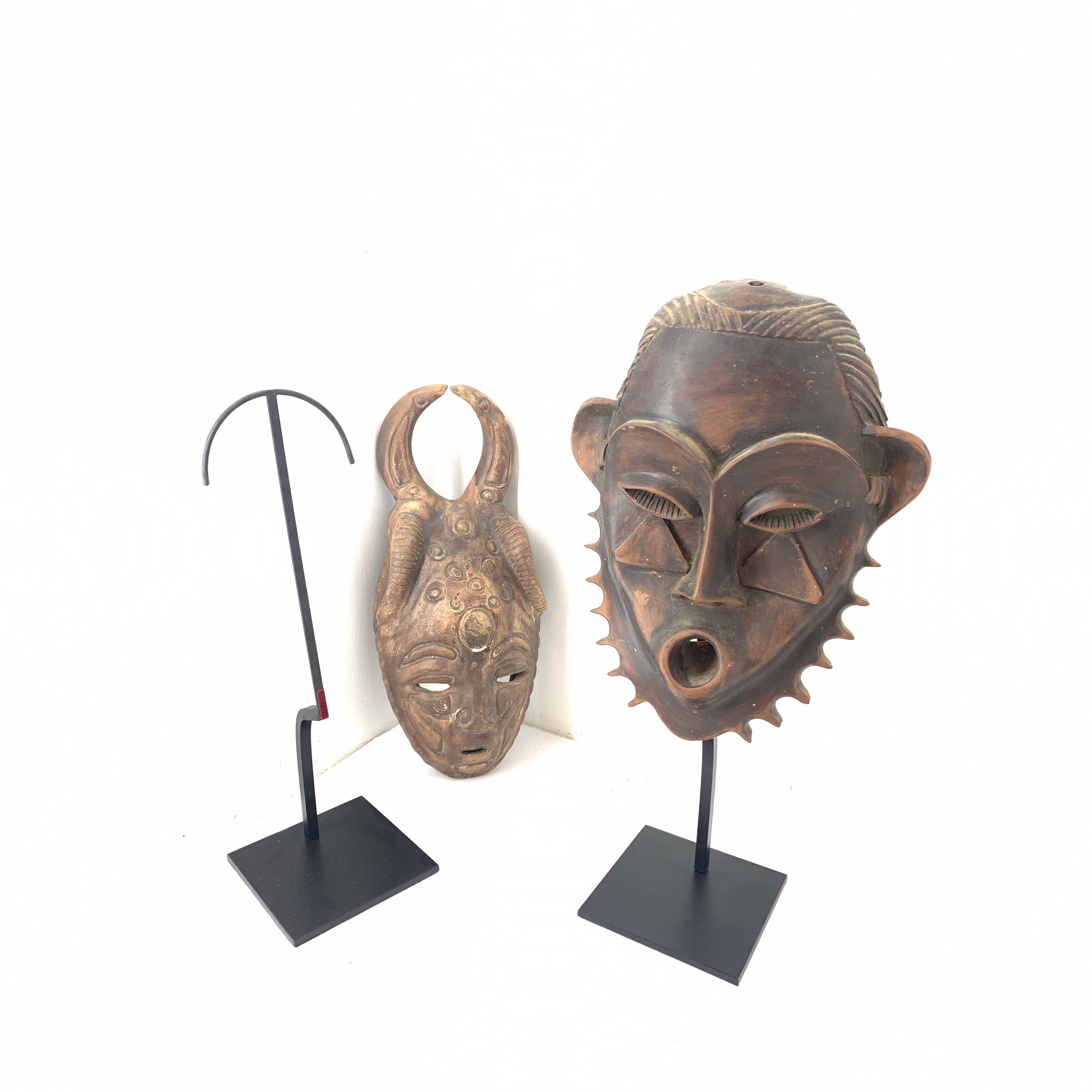 deux masque africains sur des socles en acier noir sur fond blanc 