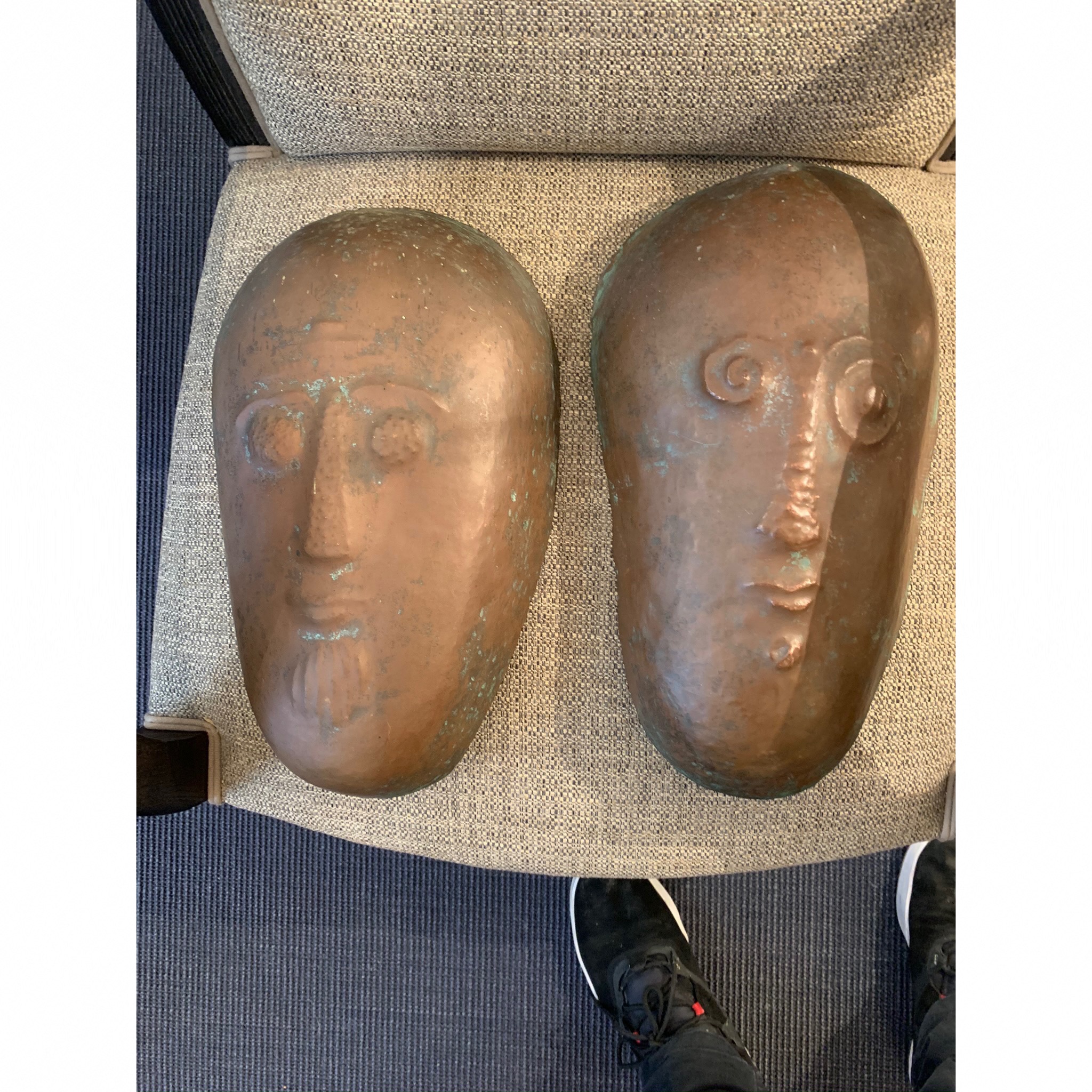 paire de masque en cuivre art contemporain pos sur un fauteuil 